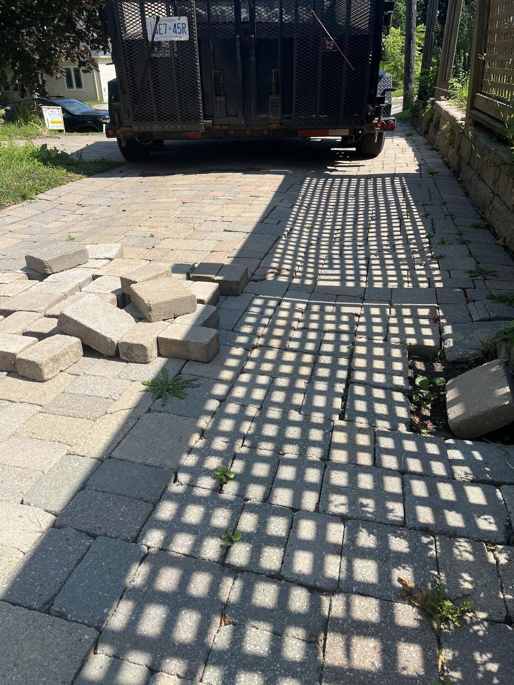 Before: settled interlock walkway with pavers lifted and stacked to the side, weeds growing through the joints