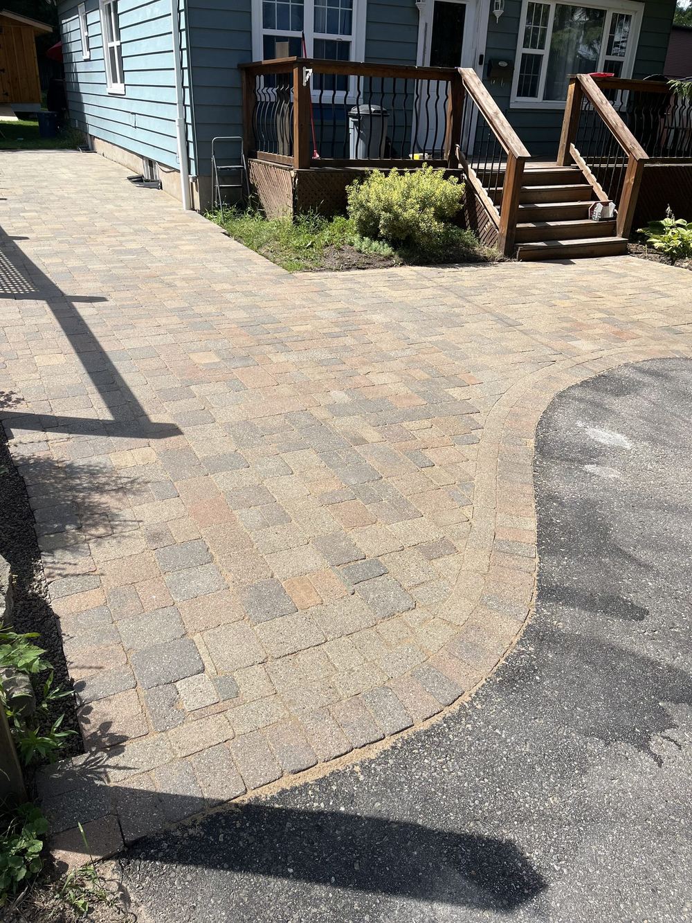 After: new interlock apron where the relaid walkway meets the asphalt driveway, cut on a clean curve
