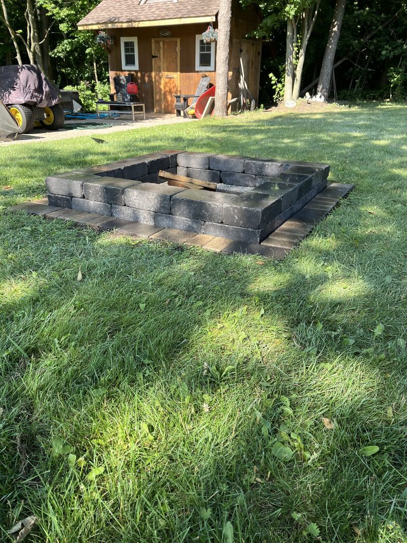 Square fire pit built in stacked wall block on a back lawn