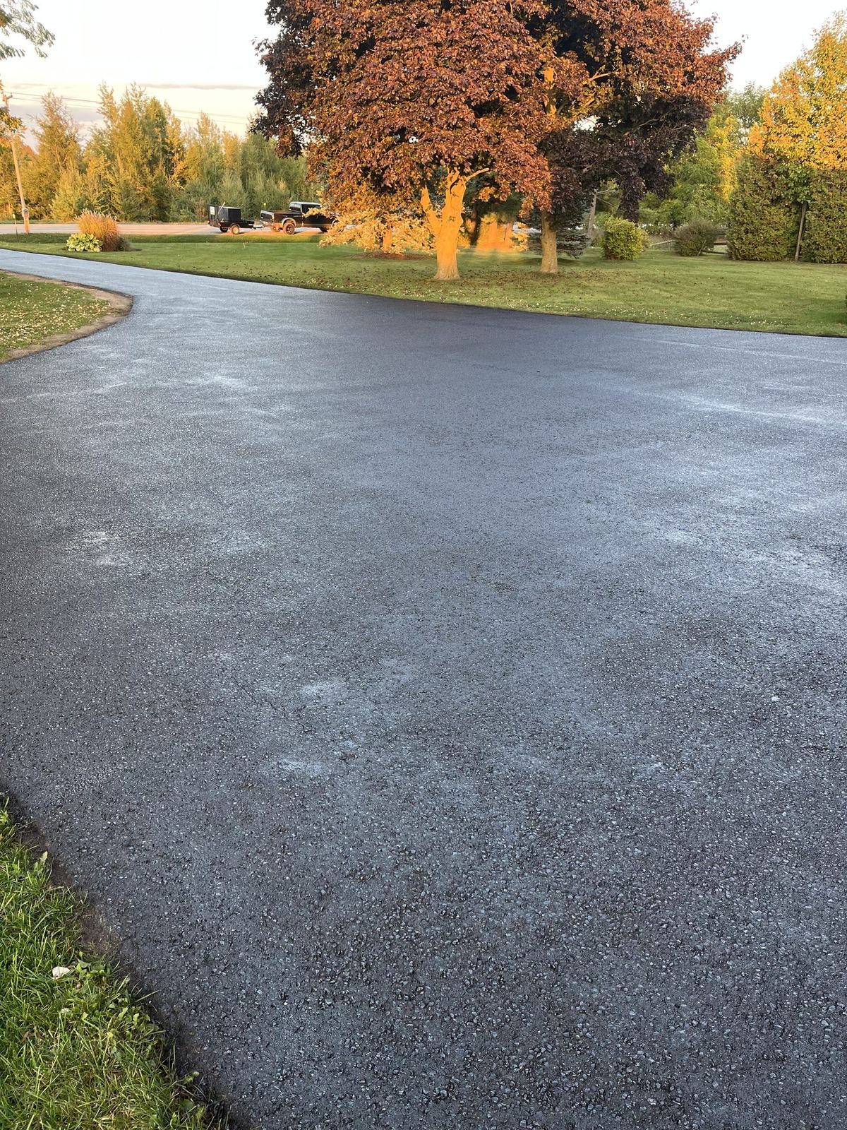Freshly sealed asphalt driveway in front of a two-car garage, still wet and edged with caution tape